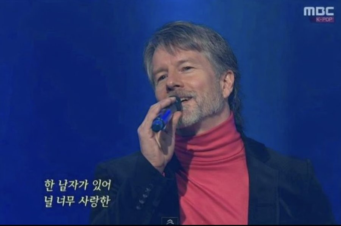 Michael Saylor, executive chairman of Strategy (formerly MicroStrategy) and prominent Bitcoin advocate, performs on stage in a red turtleneck and dark blazer, shown alongside a post highlighting major financial announcements for his company, including a 12% STRC dividend rate increase and a $20 billion share buyback program.