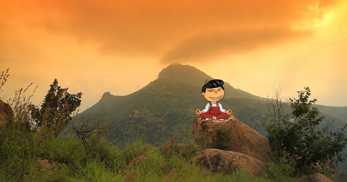 A cartoon character sitting in a meditative yoga pose on a rock, superimposed over a photograph of a misty mountain landscape at sunset or sunrise.