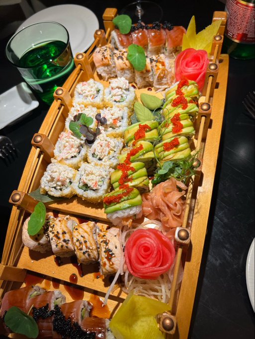 An elaborate wooden tray displays an assortment of sushi rolls, sashimi, avocado-topped rolls, pickled ginger, and roe garnishes, presented alongside a green drink. The "Smash or Pass?" prompt invites viewers to judge the visually striking and artfully arranged sushi platter.