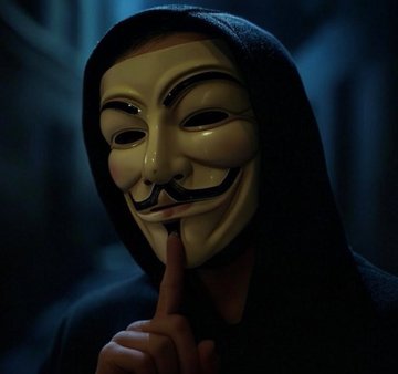 A figure wearing a Guy Fawkes "Anonymous" mask holds a finger to their lips in a silencing gesture, evoking themes of secrecy and privacy that align with the post's discussion of privacy-focused crypto projects like Monero. The dark, hooded figure symbolizes the importance of anonymity in safeguarding freedom, mirroring the post's argument that privacy is essential to the future of crypto.