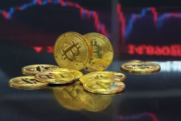 Golden Bitcoin and physical cryptocurrency coins rest on a reflective surface, set against a blurred background displaying red and blue candlestick market charts. The image visually represents the Bitcoin's surge past the $80,000 mark as highlighted in the crypto market overview.
