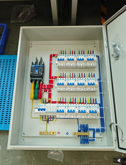 The image shows a close-up view of an electrical panel, with various colored wires and components inside. The panel has multiple switches and outlets, indicating that it controls electricity for different purposes. There are also some blue and red wires visible within the panel. The background is blurred, but there appears to be a box or container in the scene as well. The image does not provide any specific information about the content of the post, but it seems to be related to electrical work or components.
