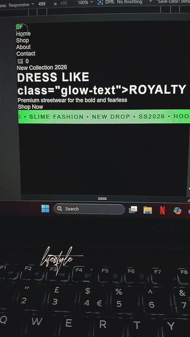 The image shows an open laptop screen displaying a webpage with text about dressing like glow-text "royalty" and a link to a new drop site called "slime fashion". The background of the image is black, which contrasts with the white keyboard in front of it.