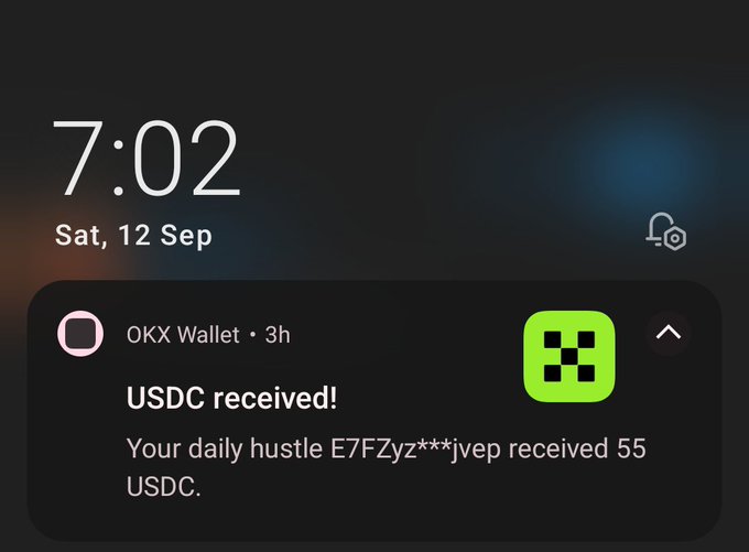 An iPhone lock screen at 7:02 on Saturday, September 12, showing a notification from OKX Wallet stating 'USDC received! Your daily hustle E7FZyz***jvep received 55 USDC.'