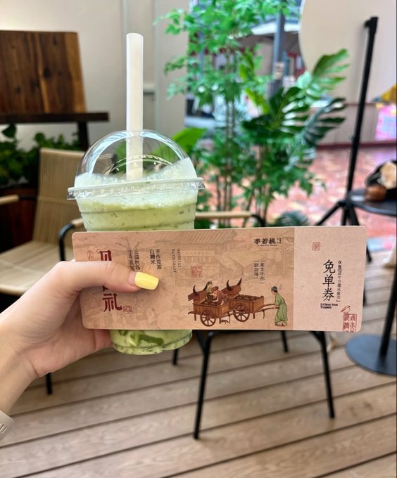 A hand with yellow nail polish holds up an iced matcha drink with a domed lid, showcasing a slip of paper with a "Free Voucher" (免单券) redemption code from the milk tea shop. The post celebrates winning a free drink after a workout, with the image displaying the actual proof of that good luck.