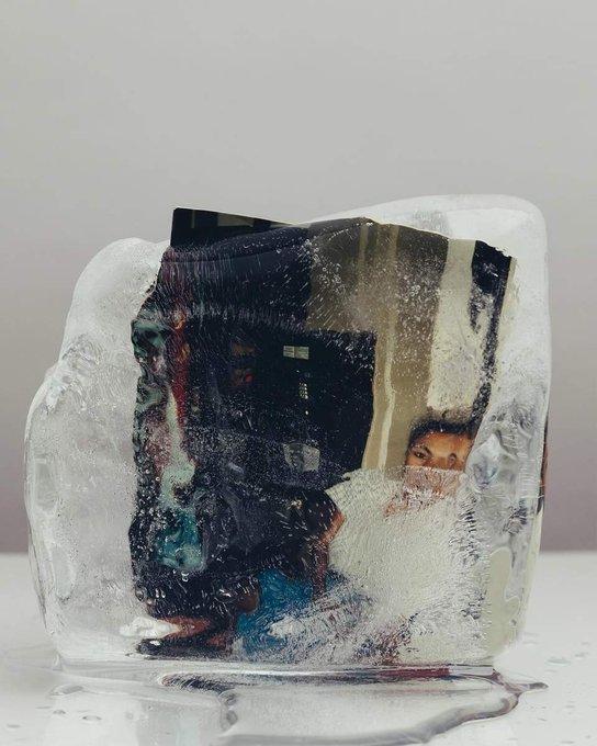 A photograph showing a printed image frozen inside a block of ice, with a child's face partially visible through the icy surface.