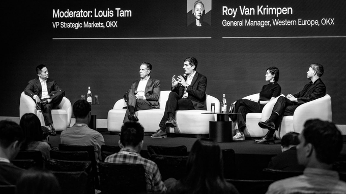 A black-and-white photo of a panel discussion with 'Moderator: Louis Tam, VP Strategic Markets, OKX' and 'Roy Van Krimpen, General Manager, Western Europe, OKX' shown in the on-screen graphics.