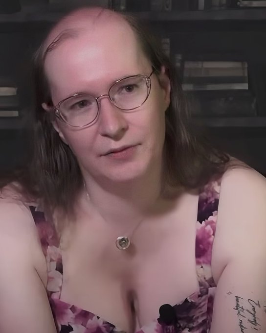 A person wearing glasses and a floral top sits in front of a bookshelf with a microphone in front of them, appearing to discuss the ZCASH dev's price action in what looks like a crypto commentary or livestream setting, addressing whether the cryptocurrency is poised for a short position.