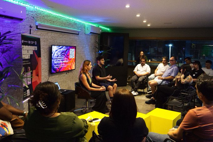 A 'COMMBUYS BUILDER NIGHT' panel discussion event with two speakers seated before an audience, featuring a screen displaying 'CHAMPIONS IN ACTION'.