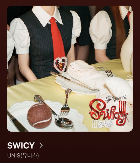 An album cover or promotional image showing girls in white puffy-sleeve shirts with red ties and dark vests, with a chocolate cake in the foreground; text reads 'SWICY' and 'UNIS (유니스)'.