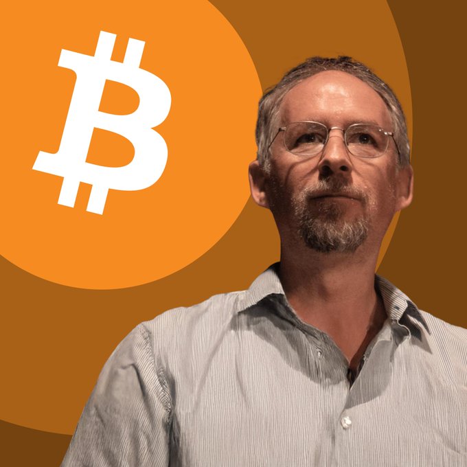 Adam Back stands in front of a large Bitcoin (₿) logo backdrop, with the accompanying quote emphasizing his view that Bitcoin is owned by humanity rather than its developers, and that protocol changes require user consensus—especially regarding spam on the timechain.