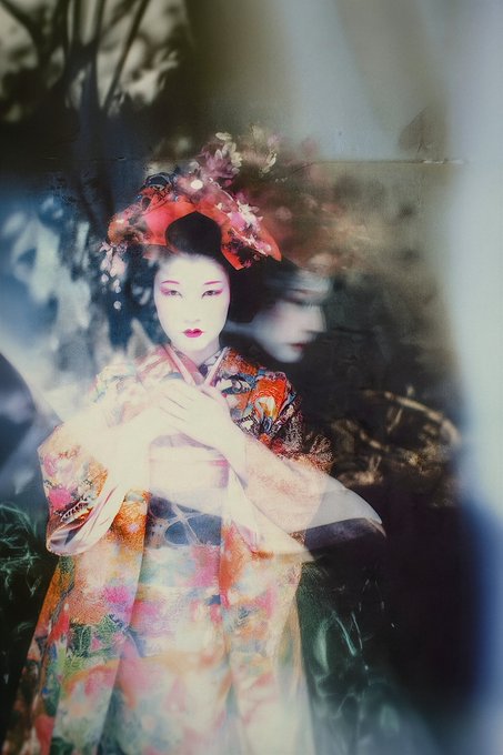An ethereal, double-exposure style photograph portrays a woman dressed as a traditional Japanese geisha, with overlapping translucent images and soft, colorful textures blending into the background.