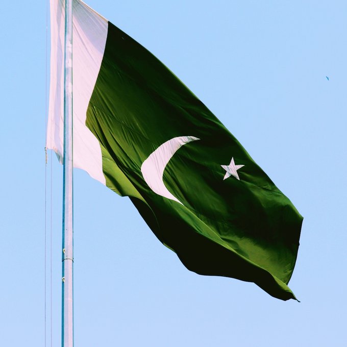 The flag of Pakistan waves against a clear blue sky, its green field with white crescent and star prominently displayed. The image visually anchors the news of Pakistan's new crypto regulatory framework, as the Virtual Assets Regulatory Authority begins accepting license applications from virtual asset service providers.
