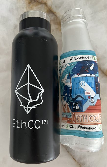 Two EthCC[7] branded bottles—one matte black water bottle featuring the Ethereum logo and a white bottle with a colorful illustrated design—rest on a marble surface. The swag appears to be from the Ethereum Community Conference, likely collected as promotional items, but shows no direct connection to the post's discussion about EthraShip's maritime intelligence layer for tokenizing real-world assets.