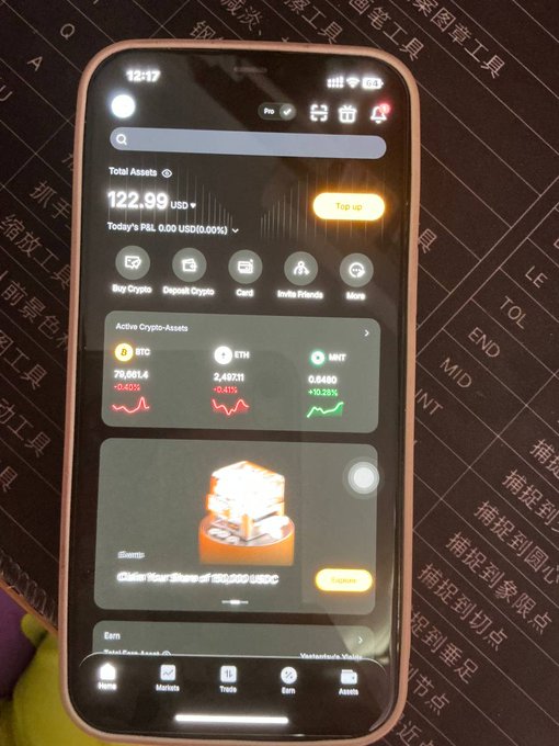 A smartphone displays a cryptocurrency app showing total assets of 122.99 USD, with active crypto assets including BTC, ETH, and MNT, along with a Burn event offering 180,000 USDC.
