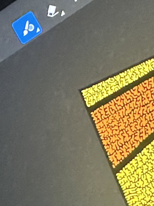 A dark textured surface with a blue 3D icon in the upper left and patterned yellow and orange rectangular areas on the right side.