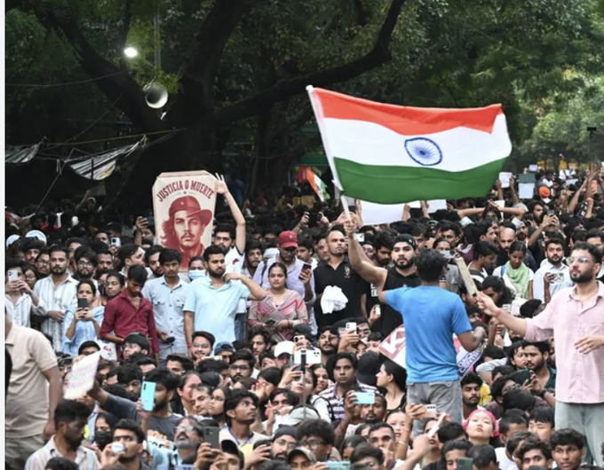 A massive crowd gathers at a CJP protest, with participants waving the Indian flag and a sign displaying "JUSTICE & DIGNITY" alongside a portrait, while many hold up phones to record. The image's vast assembly of engaged young people illustrates the social activism the post hopes to channel toward crypto education and financial opportunities.