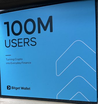 A blue Bitget Wallet merch box celebrating the platform's 100M users milestone, featuring the tagline "Turning Crypto into Everyday Finance" alongside the Bitget Wallet logo, corresponding to the anniversary merchandise referenced in the post.
