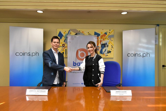 Coins.ph and Bayad Center representatives Jenny S. Gatuslao and Amira Alawi shake hands at a partnership signing, symbolizing Coins.ph's expansion to nearly 300 billers and 17 payment categories in its app.