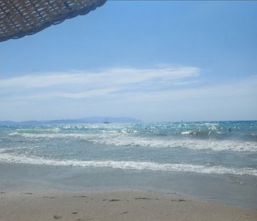A calm ocean view with gentle waves meeting the shore under a bright blue sky, framed by the edge of a woven beach umbrella. The serene seaside scene complements the post's reflective tone, symbolizing a moment of rest and hope for greater opportunities ahead after the holiday break.