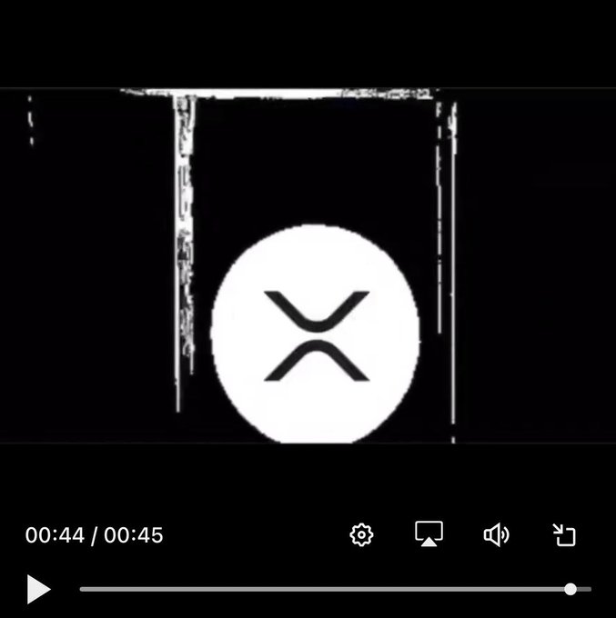 A black-and-white screen shows a large white circular icon with an hourglass-like symbol, above a video player timeline labeled “00:44 / 00:45.” The accompanying post suggests a crypto/XRP conspiracy about the “Riddlers,” AI, and an impending system crash.