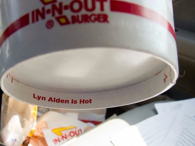 A close-up view of an In-N-Out Burger cup, with the text "Lyn Alden Is Hot" printed in red along the inside rim of the cup's lid.