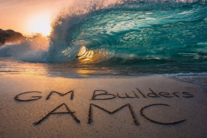 A scenic beach photo at sunset with a crashing wave, and 'GM Builders' and 'AMC' written in the sand on the beach.