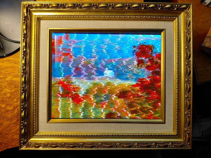 A framed abstract painting in an ornate gold frame, depicting vibrant red, blue, green, and yellow brushstrokes with a vertical streaky texture.