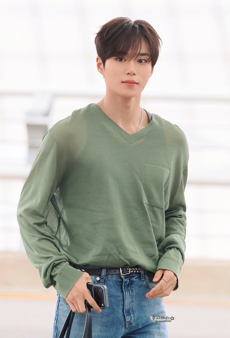 A photo of a young man wearing a green V-neck sweater and blue jeans, holding a phone, with a watermark 'A4M2U' in the corner.