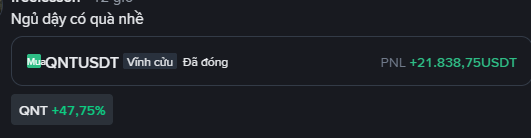 A dark-themed financial notification in Vietnamese reading 'Ngủ dậy có quà nhé' (There's a gift when you wake up), showing the QNT/USDT trading pair with a gain of +21,838.75 USDT and the QNT token up +47.75%.
