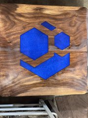 A wooden block featuring a blue inlaid logo resembling a geometric smiley face with a hexagon eye.