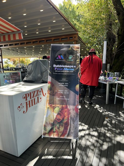 An outdoor banner advertising 'Bubblemaps x Four Meme' private lunch in Klay 2025, sponsored by Bubblemaps and Four, with a person in a red shirt walking nearby.