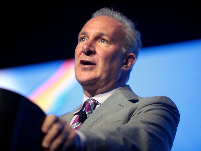 An older man with gray hair, wearing a gray suit and pink striped tie, speaks at a podium with a small microphone. The image relates to the post by likely depicting Peter Schiff, the financial commentator known for his criticism of Bitcoin and advocacy for gold, captured mid-speech as he discusses his bearish outlook on BTC relative to gold.