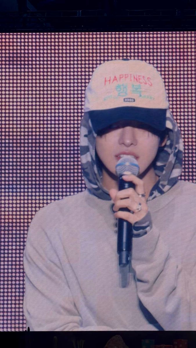 The image features a person wearing a baseball cap, holding a microphone, and standing against a pink background with white dots. There are also some text elements visible in the image that read "260612 LEO for day1 fancon soundcheck!". The caption suggests that this photo might be related to a concert or event where the person is either performing or working behind the scenes as a soundchecker, ensuring everything sounds perfect before the event begins.