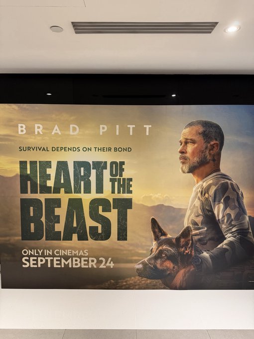 A movie poster in a cinema lobby advertises 'HEART OF THE BEAST' starring Brad Pitt, with the tagline 'SURVIVAL DEPENDS ON THEIR BOND' and a release date of 'SEPTEMBER 24'.