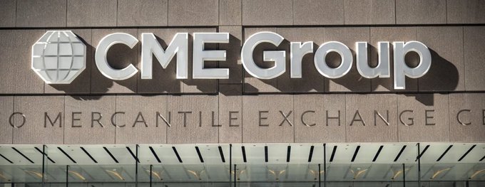 A photograph of the exterior signage for CME Group, featuring its globe logo and the text "CME Group" and "MERCANTILE EXCHANGE" on a stone wall.