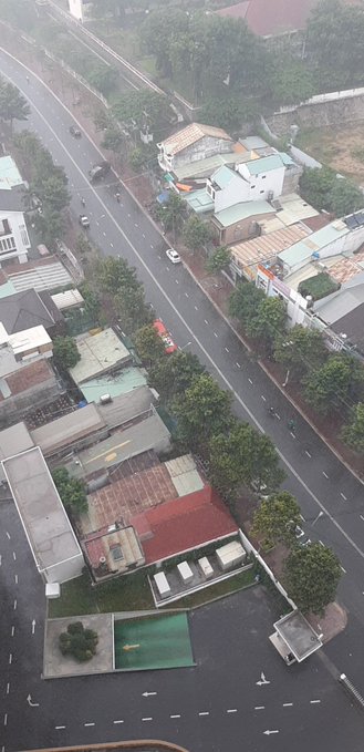 An aerial view of a residential street with houses, a small swimming pool, and a red truck parked along the road, taken from a high vantage point.