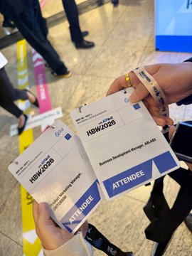 Two hands hold attendee badges reading 'HBW2025' and 'ATTENDEE' for the 'Business Development Manager - All AB' role.