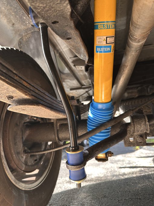A close-up photo of a yellow Bilstein shock absorber installed on a vehicle's suspension system near the wheel well.