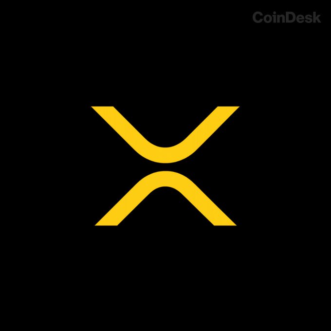 The image displays a yellow XRP cryptocurrency logo on a black background, with a "CoinDesk" watermark in the upper right corner. The logo represents the XRP token discussed in the article about XRP ETFs attracting significant inflows despite the broader crypto market downturn.