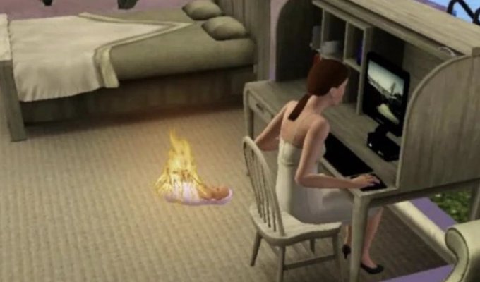 A 3D animated scene (appearing to be from The Sims) of a woman in a towel sitting at a desk using a computer, while a small fire burns on the carpet nearby.