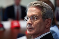 A close-up image shows a gray-haired man wearing glasses and a dark suit, looking serious and contemplative, with a red name placard partially visible on the table in front of him. The image suggests a formal or governmental setting, which contrasts with the post's focus on cryptocurrency tickers like $XRP, $SOL, and $CC, possibly hinting at regulatory or financial discussions relevant to the crypto market.