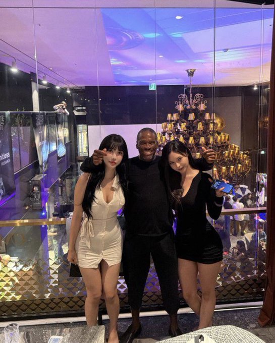 The image shows three people posing together, with one of them holding a cell phone. They are standing next to each other near a large chandelier or crystal tree, which adds an elegant touch to their gathering. The background reveals that they are in a room filled with various objects and decorations, including a dining table and chairs.

The post seems to be related to the sale of a house for 150K, as suggested by Arthur Hayes' statement about Iran. This information is not directly visible in the image but can be inferred from the context provided.
