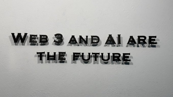 Black metallic letters mounted on a white wall spell out "WEB 3 AND AI ARE THE FUTURE," visually embodying the company's forward-looking motto about emerging technologies.