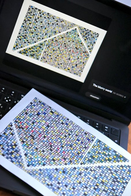 A laptop screen displays an image of a mosaic with geometric triangular shapes made of small squares, with a printed copy of a similar colorful mosaic artwork resting on the keyboard below.