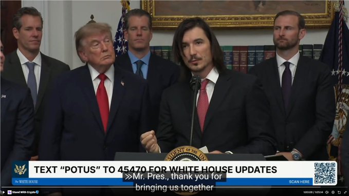 A man is speaking at a podium with Donald Trump and others behind him, while text on screen offers "WHITE HOUSE UPDATES" via text to 45470 and a QR code. This image shows what appears to be Donald Trump at the White House, relevant to the post's mention of "$INDEX founder giving a speech at the White House."