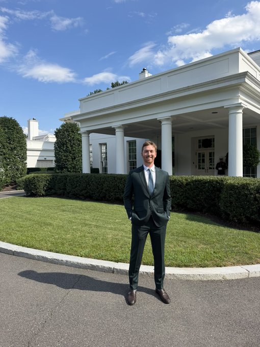 Jared Kushner stands in a dark suit in front of a white columned building, likely the White House.