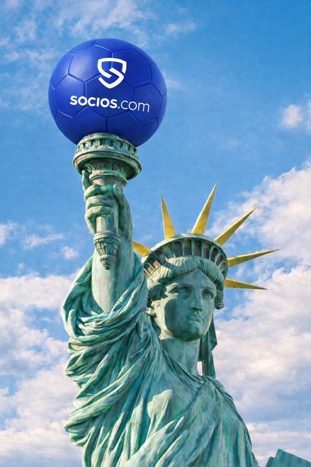 The image features a statue of Liberty, which is a green marble sculpture located in New York City. The statue is holding up a soccer ball with its right hand while standing on a pedestal. In the background, there are some clouds visible against a blue sky. The caption above the image reads "This was always the direction. All roads lead to the SportFi Hub." This phrase suggests that sports and physical activities have been an integral part of American culture for many years.