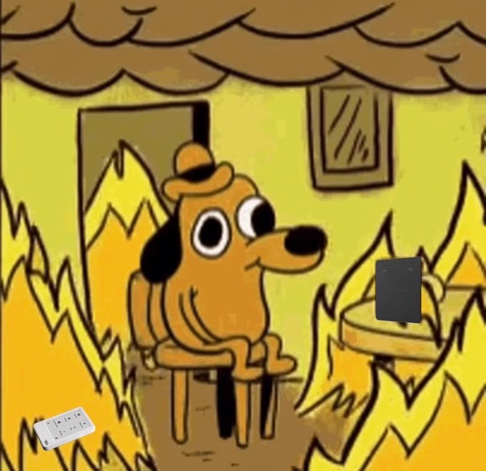 A cartoon dog sits in a burning house, surrounded by flames and smoke, with a smartphone and what appears to be a recovery seed phrase visible. The post relates to the meme as a humorous warning about securing crypto recovery keys — even in a disaster scenario, having access to your ledger recovery phrase is what saves your assets.