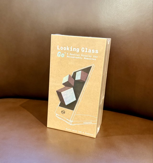 A sealed product box for 'Looking Glass Go - A Spatial Display for Holographic Memories,' shown sitting on a brown leather surface, marked as 'Made with iOS & Android' compatible.